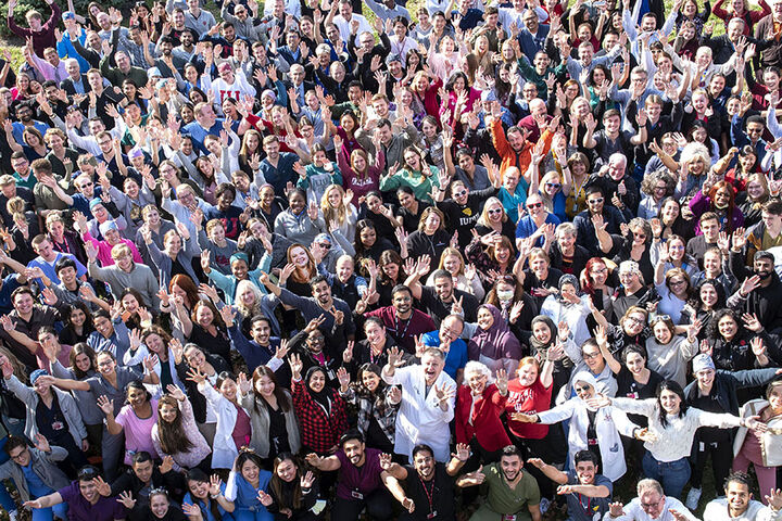 A large group of IU School of Dentistry students and professors wave at the camera.